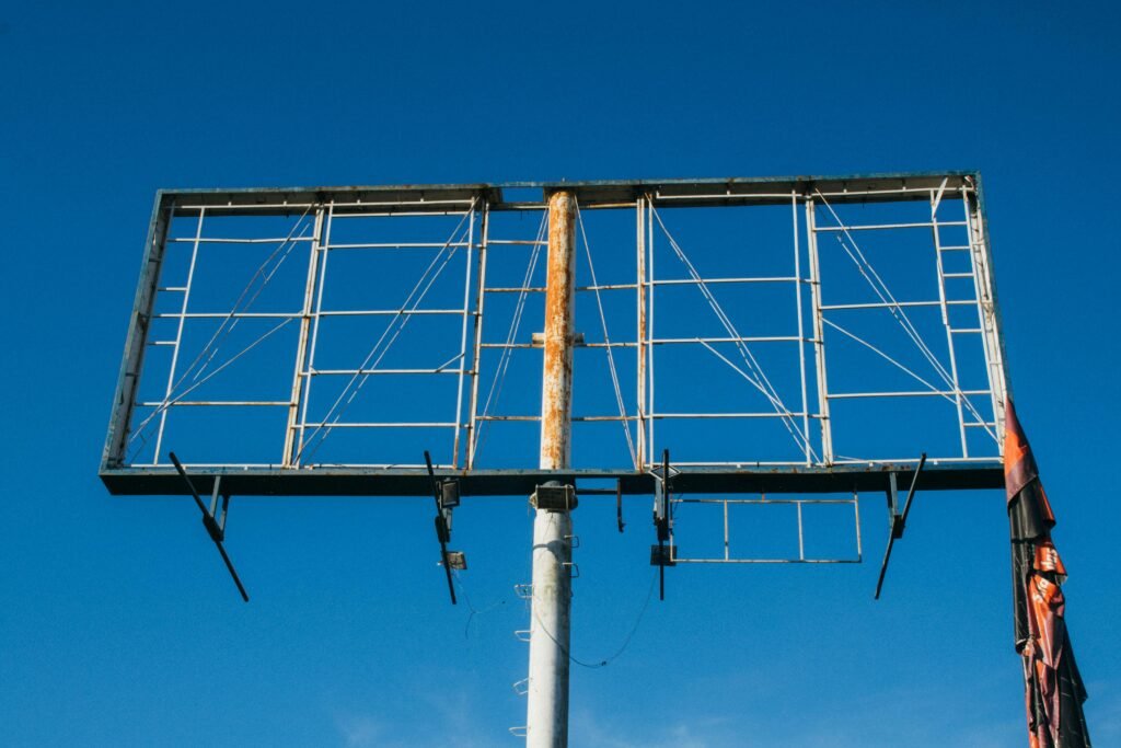 A large rusted billboard structure reaching into a clear blue sky.